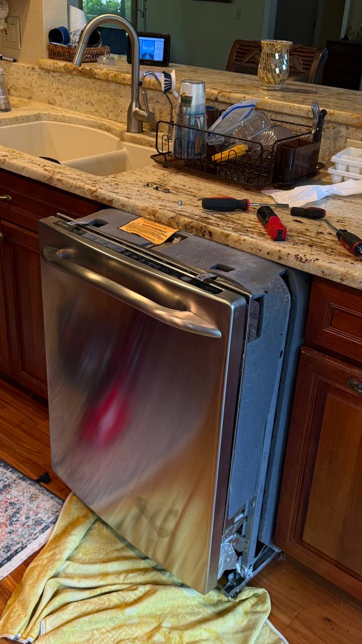 Technician repairing a GE Profile dishwasher in a Naples kitchen